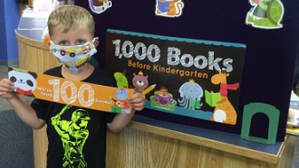 child standing holding a sign that says "I read 100 books"