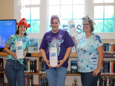Three Librarians holding interactive movie themed bags