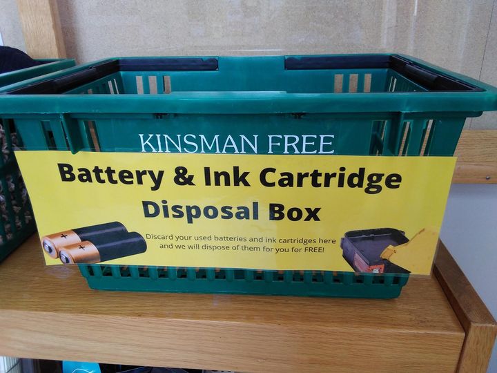 Green Basket with yellow sign that says "battery & ink cartridge disposal"