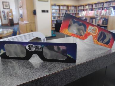 two pairs of eclipse glasses resting on a counter