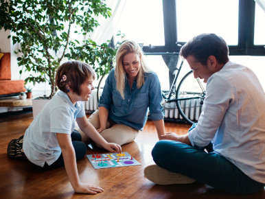 Family of three sitting on the floor around a board game