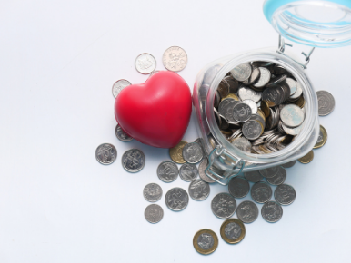 a jar full of coins with coins scattered around it and a red heart