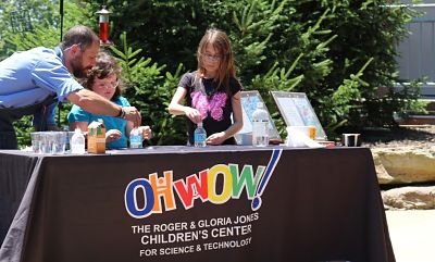 Teacher helping two young girls do a science experiment
