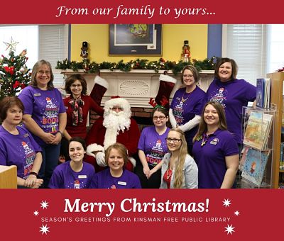 Group of women sitting and standing around santa smiling for a photo