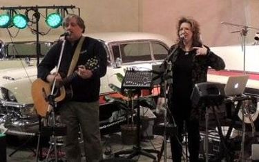 Pictured, the Band Take II, a woman singing and a man singing and playing guitar