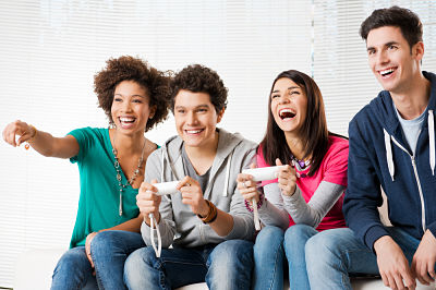 A group of teens playing Wii and laughing