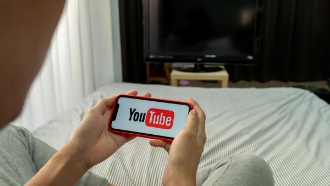Picture of a person holding a phone with YouTube on the screen